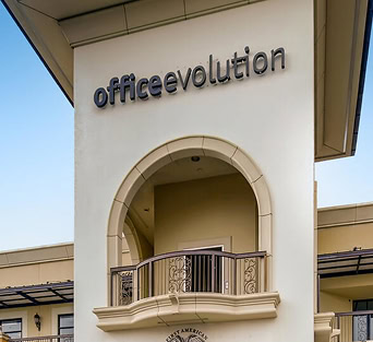 Office Evolution franchise sign on building exterior, promoting flexible coworking and office solutions in Spain.