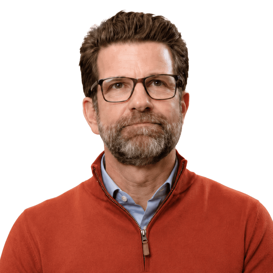 Professional middle-aged man with glasses and a beard, wearing a rust-colored sweater and blue shirt, looking confidently at the camera.